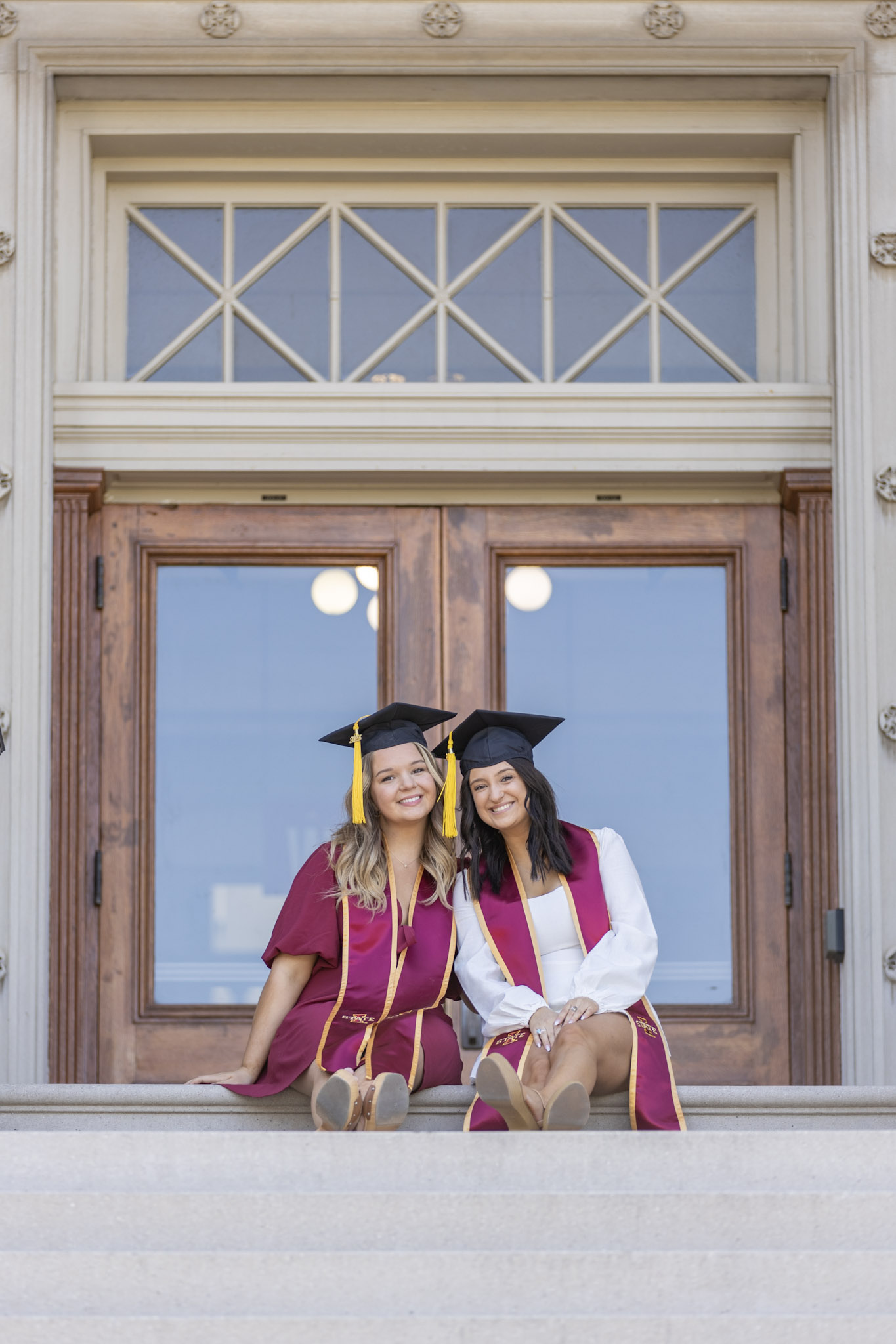 A pair of graduating seniors pose at Beardshear Hall.